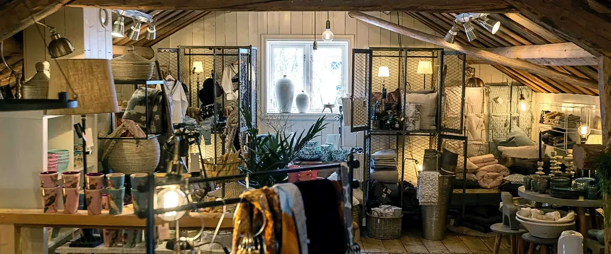Varm butiksmiljö i magasinet med rustika takbjälkar, keramik och mjuka textilier
